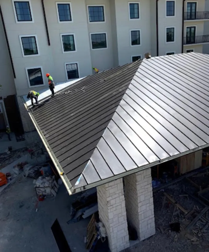 Crew installing standing seam metal roof panels on a commercial project in Londonderry